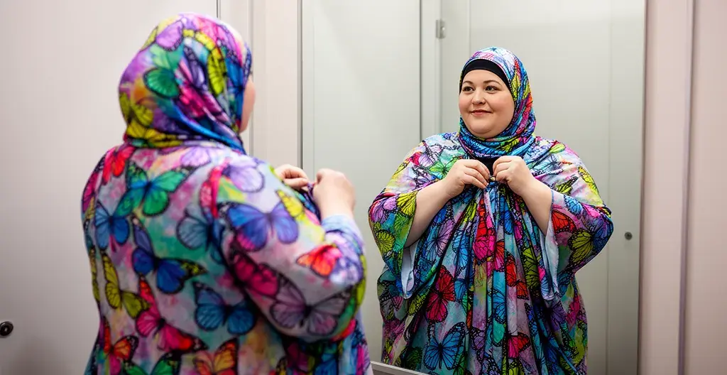 Femme ronde essayant un burkini papillon ample devant miroir cabine